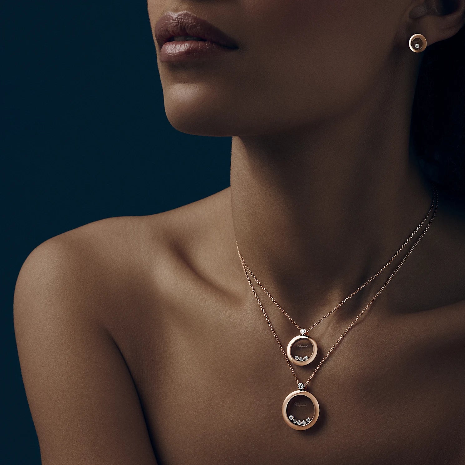 A woman wearing the layered rose gold diamond pendant necklace against shadow.