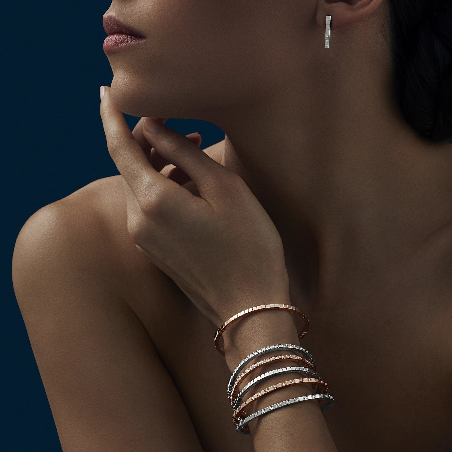 Model wearing stacked gold bangles.