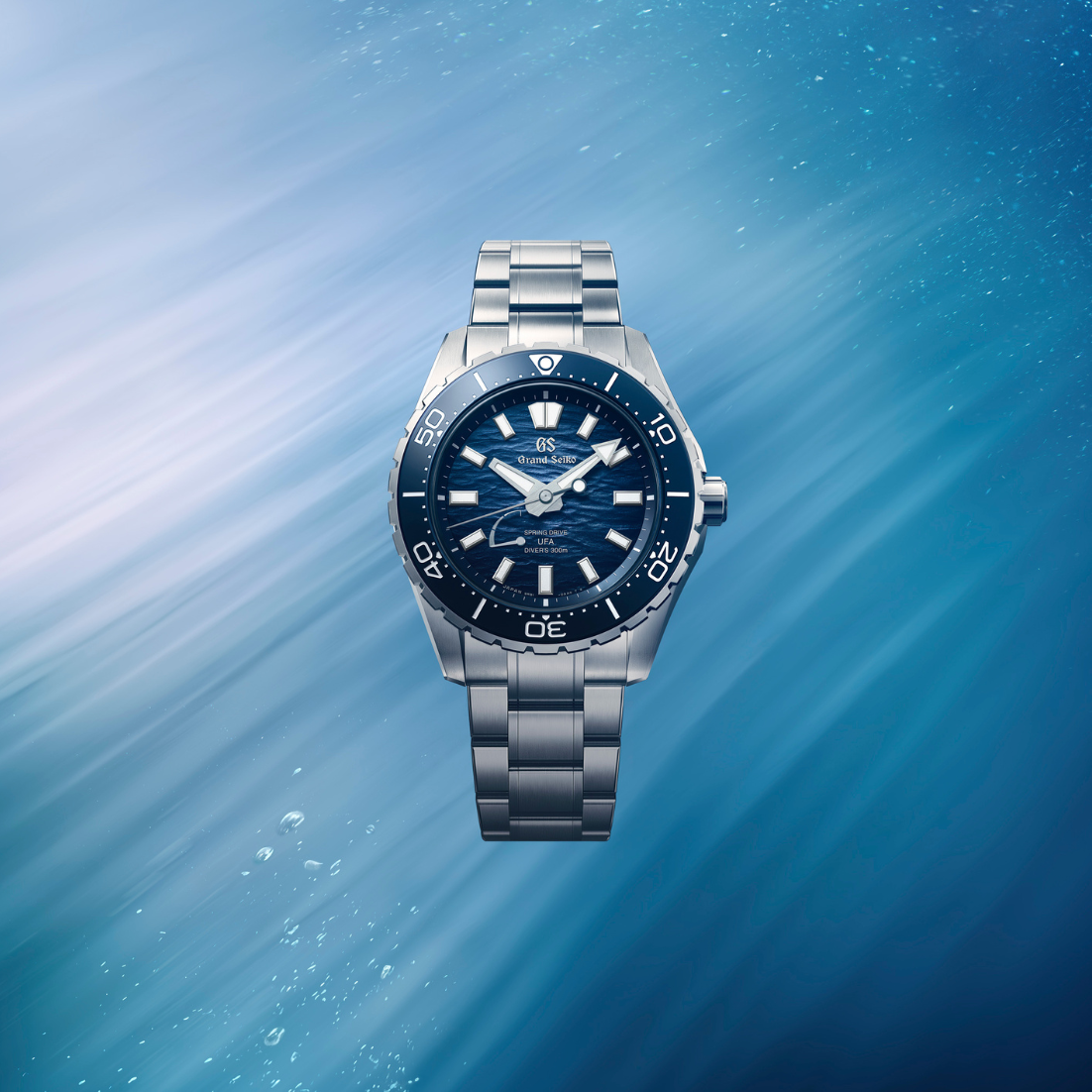 Wide cinematic banner of the watch positioned against a textured grey studio background.