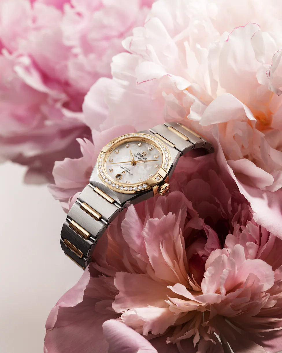 Two-tone Omega watch resting on pink peony petals.