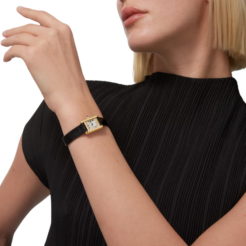 Gold Cartier Tank watch worn on a wrist.
