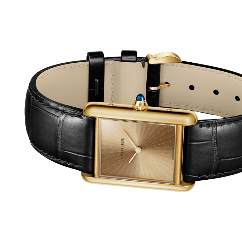 Angled view of gold watch and leather strap.