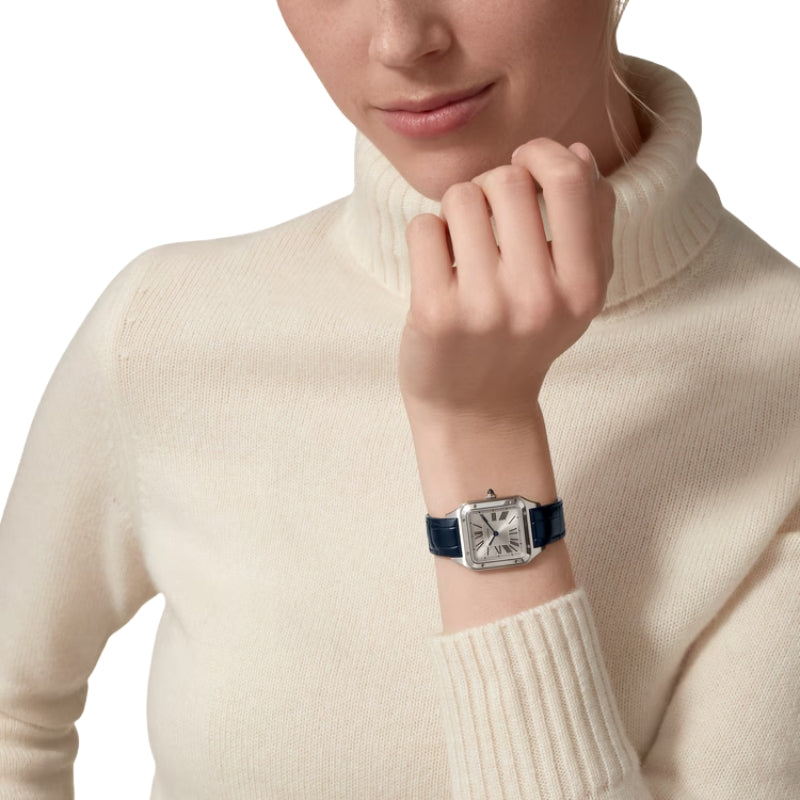 Woman wearing silver Cartier watch with blue strap.