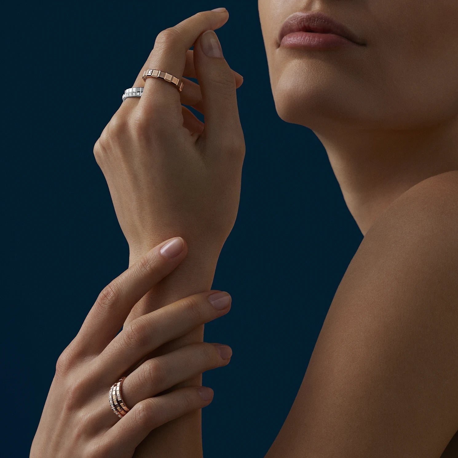 A woman modeling several gold rings on her hands and fingers.