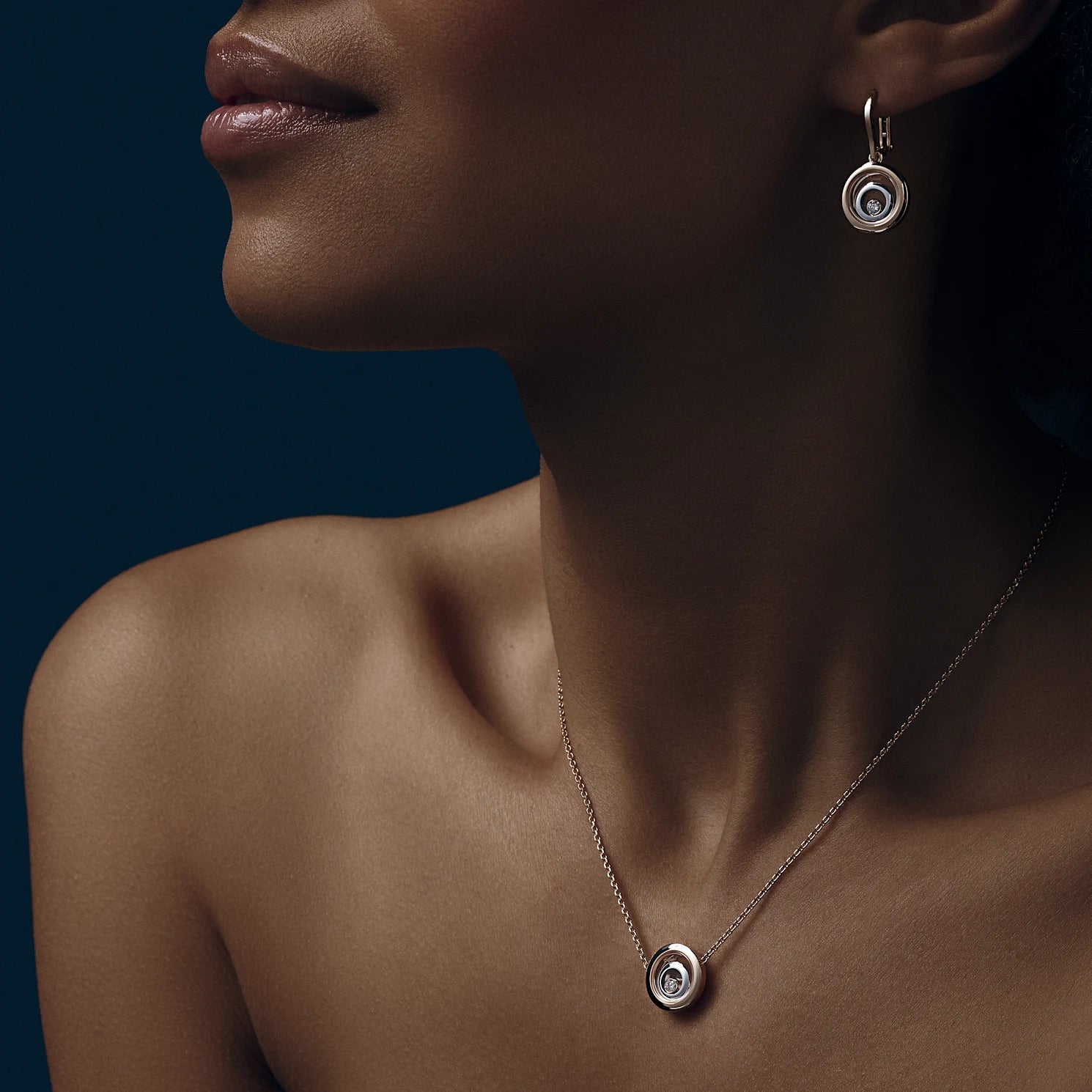 A woman wearing the rose gold drop earrings and a matching necklace.