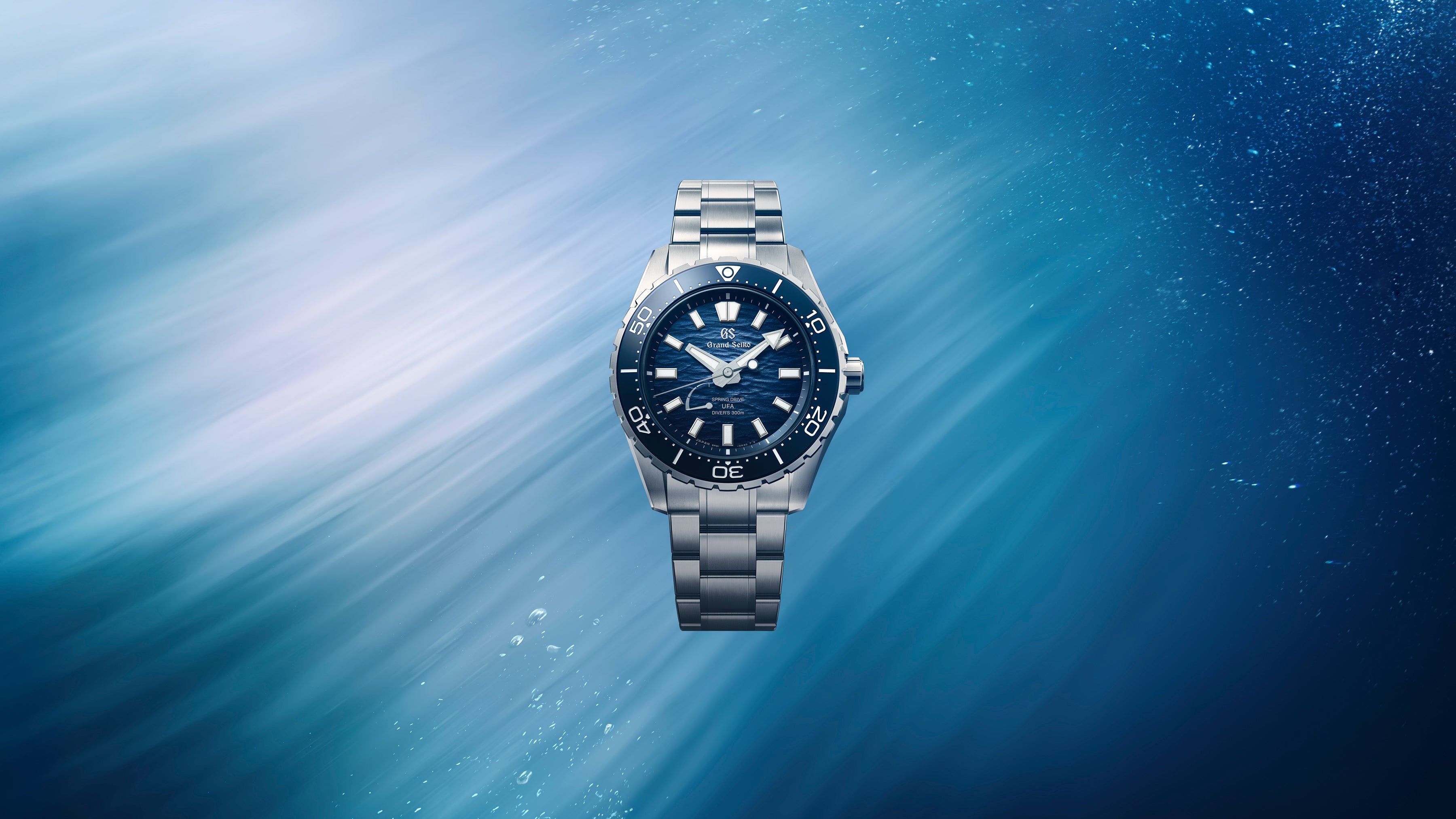 Wide cinematic banner of the watch positioned against a textured grey studio background.